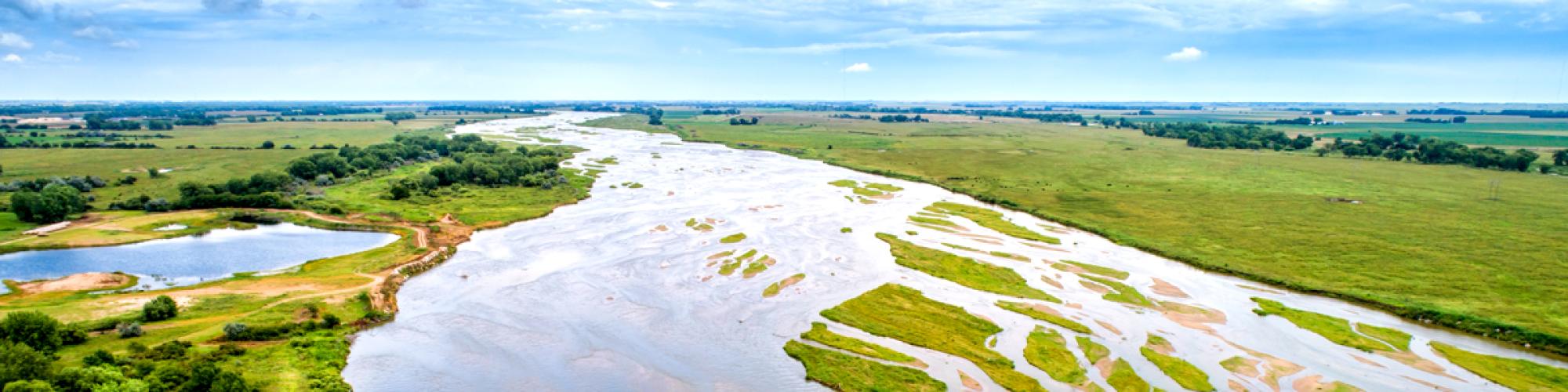 image of a river running through green fields