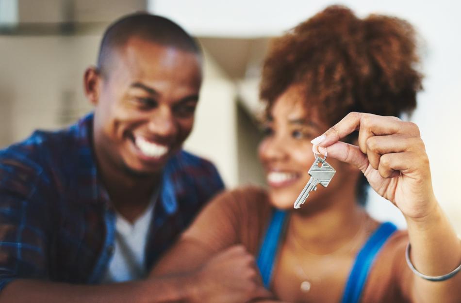 husband and wife smiling while hold a key