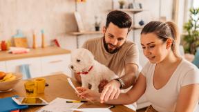 A guy and girl reviewing their bills in the kitchen. 