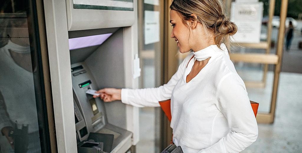 Person putting their debit card into an ATM.