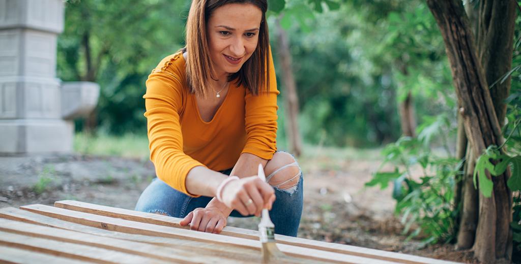 A lady painting wooden planks. 