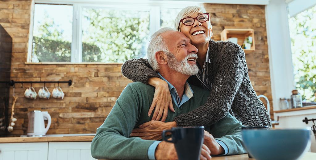 An older couple hugging in the kitchen. 