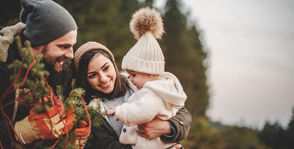 A mother and father with their daughter outside in nature.