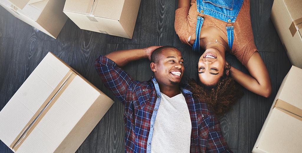A couple taking a break from moving to lay on the floor together.
