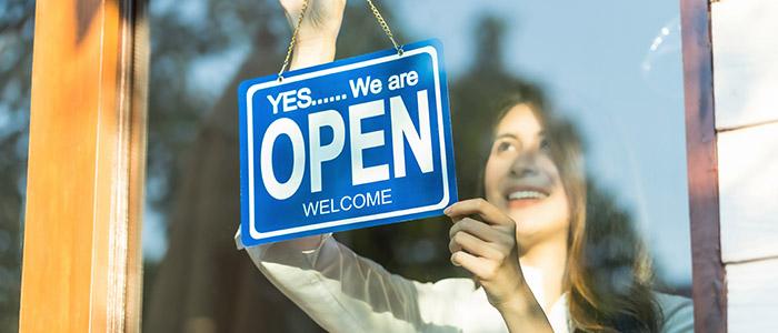 businesswoman hanging open sign in window